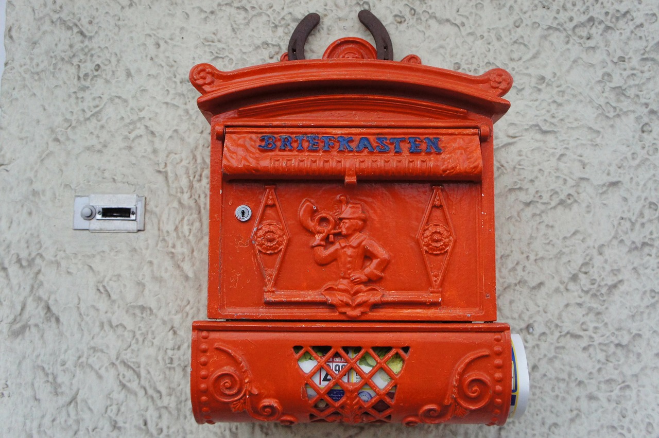 Roter Briefkasten mit Zeitungsrolle